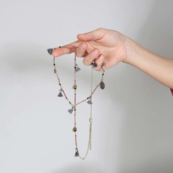 A delicate and interesting piece, this handmade necklace has 8 little grey tassels and 7 gold discs hanging from a gold chain which part is wrapped in pink and raspberry thread. 

