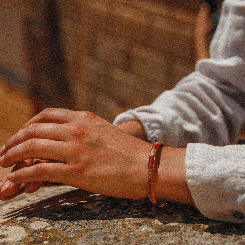 Enhance your wrist with this golden/brass effect open cuff bracelet, with burnt orange, burgundy red and gold wrapped thread.