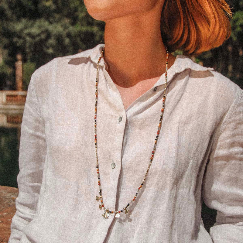 This delicate beaded necklace will be a real talking piece, with its 5 little gold discs and black, grey, red, ochre and gold beads. 
